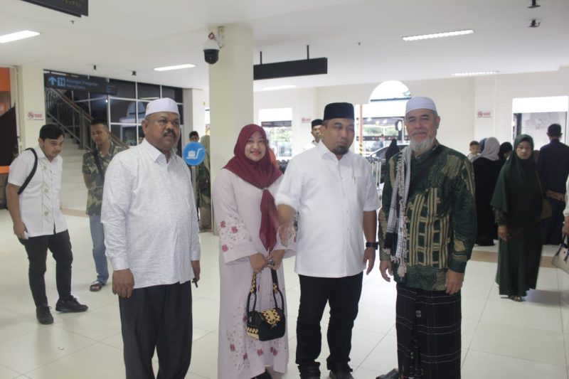 Pj Bupati Aceh Besar, Muhammad Iswanto SSTP MM didampingi istri yang juga Pj Ketua Tim Penggerak (TP) PKK Aceh Besar, Cut Rezky Handayani SIP MM, dan Kadis Syariat Islam Rusdi SSos MSi foto bersama saat mengantar sekaligus melepaskan keberangkatan ulama yang juga Pimpinan Dayah di Aceh Besar, berangkat menunaikan ibadah umrah melalui Bandara Sultan Iskandar Muda (SIM), Blang Bintang, Aceh Besar, Minggu (6/8/2023) pagi.