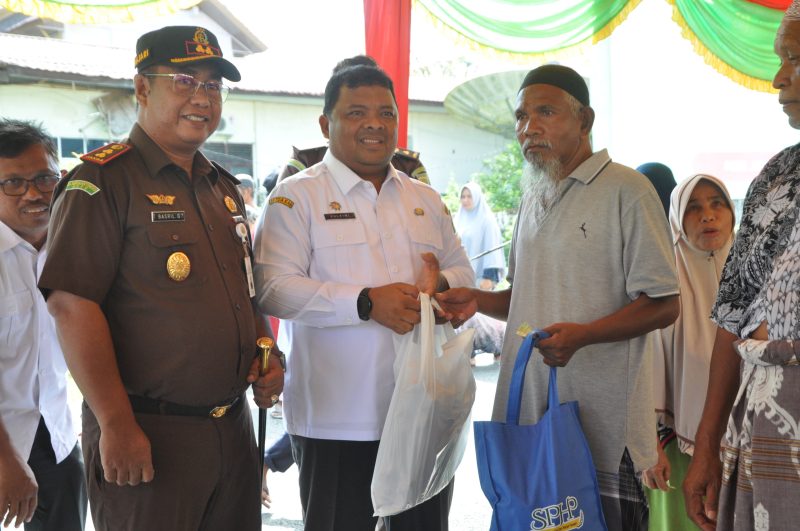 Sekda Aceh Besar Drs Sulaimi MSi menyerahkan paket belanjaan masyarakat Jantho pada pelaksanaan Bazar Pangan Murah, di Depan Kantor Kejari Kota Jantho, Rabu (3/4/2024).