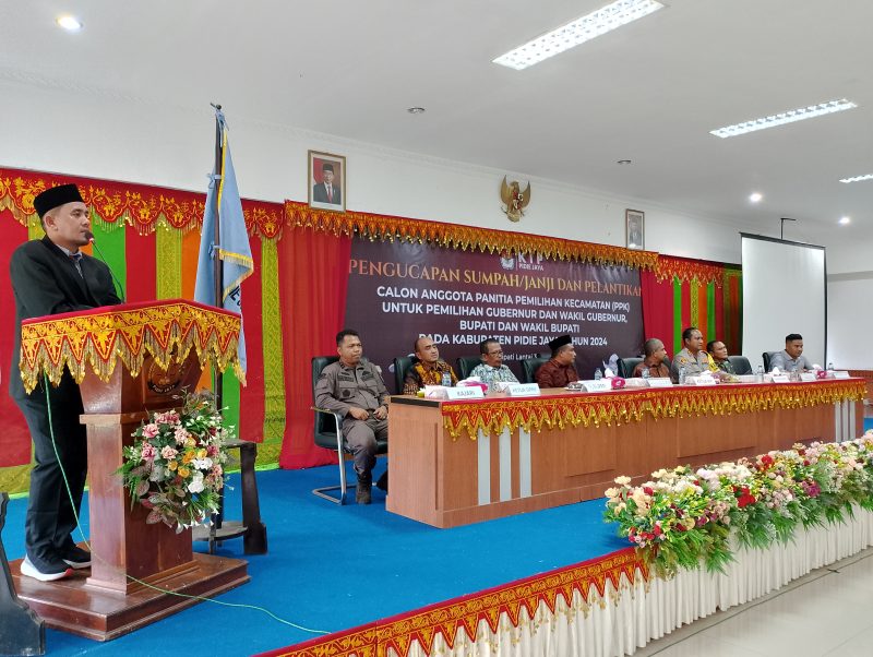 Ketua KIP Pidie Jaya, Iskandar, S.Sos ( yang berdiri di mimbar) sedang memberikan kata-kata sambutan di acara pelantikan dan pengambilan sumpah PPK Pilkada 2024, Aula Cot Trieng 3, Kamis (16/5/2024). (Foto|Muhammad Rissan/NOA.co.id)