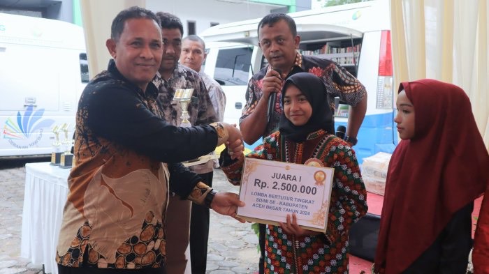 Pelajar MIN 27 Aceh Besar, Nafla Syakira, saat menerima hadiah juara satu dari lomba Bertutur yang digelar Dispersip di Kota Jantho. (Foto: noa.co.id/FA)