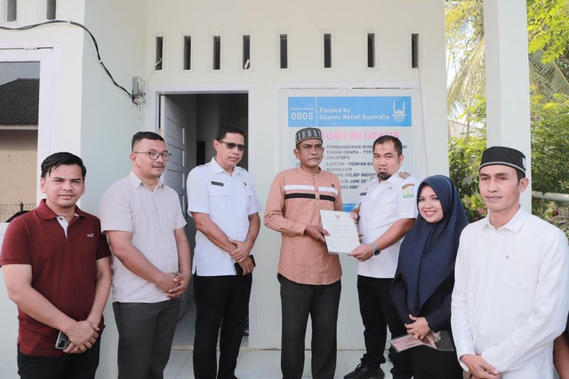 Pj Bupati Aceh Besar Muhammad Iswanto menyerahkan sertifikat rumah kepada Nurhayati salah satu penerima bantuan rumah layak huni bantuan dari Islamic Relief Indonesia dan Baitul Mal Aceh Besar di Gampong Lamteh Kecamatan Peukan Badan, Aceh Besar, Rabu (26/06/2024). Foto: MC Aceh Besar. 