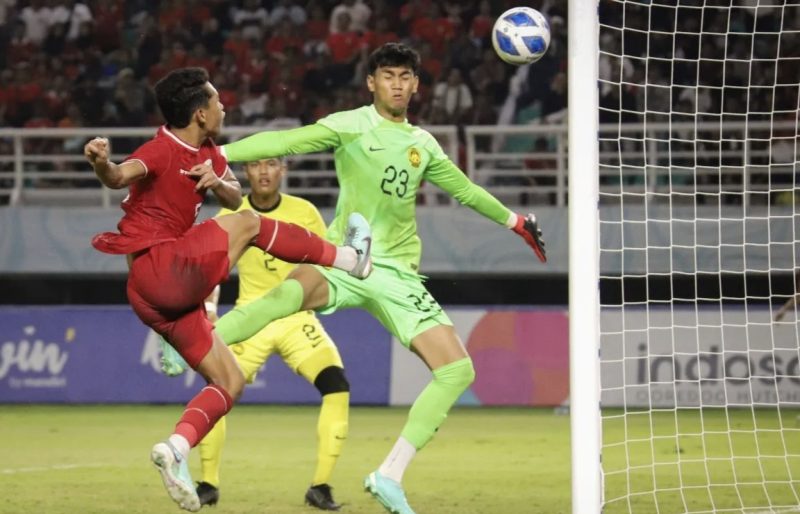 Pesepak bola Timnas Indonesia Muhammad Alfharezzi Buffon (kiri) berusaha menjebol gawang kiper Timnas Malaysia Muhammad Hazig Aiman Bin Mohd Esa (kanan) dalam pertandingan semifinal Piala ASEAN U-19 Boys Championship atau AFF U-19 di Stadion Gelora Bung Tomo, Surabaya, Jawa Timur, Sabtu (27/7/2024). (Foto: ANTARA)