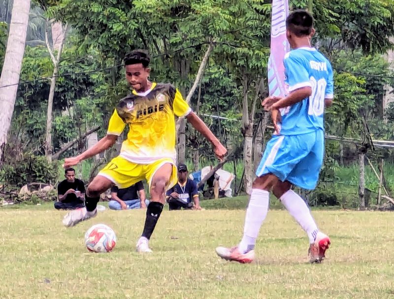 Pemain sepak bola Popda Pidie saat menggiring bola dan dibayangi pemain Abdya pada laga lanjutan Popda Aceh XVII di lapangan Matang Rayuek, Kecamatan Peudawa Kabupaten Aceh Timur, Senin, (8/7/2024). Foto: dok. Amir Sagita/NOA.co.id