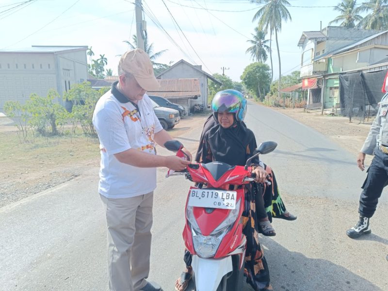 Subhan membagikan dan memasang Bendera Merah Putih secara langsung kepada pengendara sepeda motor, bertempat dijalan peukan Biluy, Darul Kamal, Aceh Besar, Jumat (02/08/2024). Foto: Mc Aceh Besar