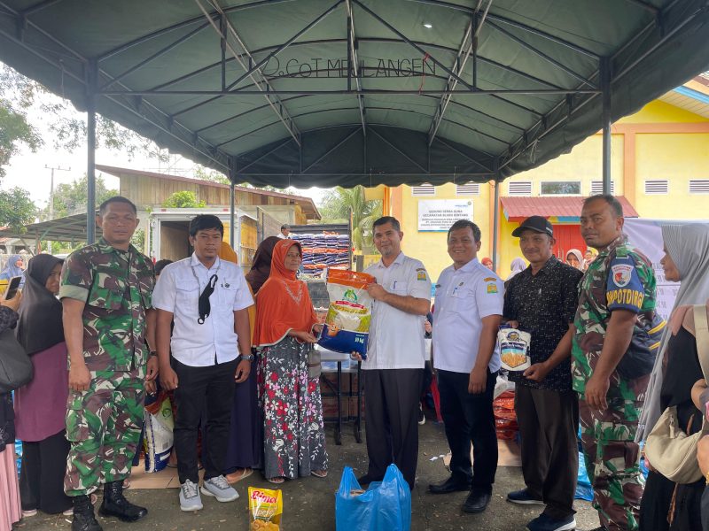 Plt Kadiskopukmdag Aceh Besar Trizna Darma ST, didampingi unsur Forkopimcam Blang Bintang, menyerahkan secara simbolis paket sembako pasar murah kepada seorang pembeli, di Halaman Kantor Camat Blang Bintang, Aceh Besar, Rabu (20/11/2024). Foto: dok. MC Aceh Besar