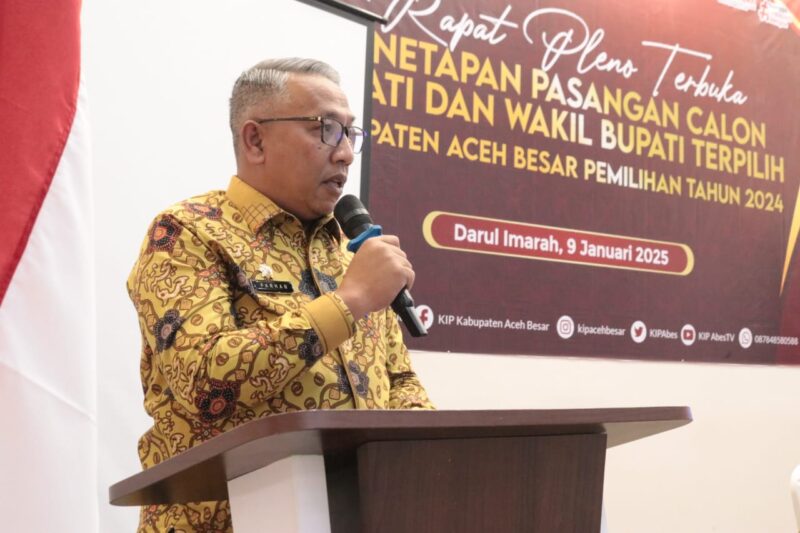 Asisten I Sekdakab Aceh Besar, Farhan AP memberikan kata sambutan pada Rapat Pleno terbuka penetapan pasangan calon Bupati dan Wakil Bupati terpilih periode 2025-2030 yang diselenggarakan oleh Komisi Independen Pemilihan (KIP) Kabupaten Aceh Besar, di Orion Hall, Garot, Darul Imarah, Kamis (09/01/2025). Foto: Dok. MC Aceh Besar